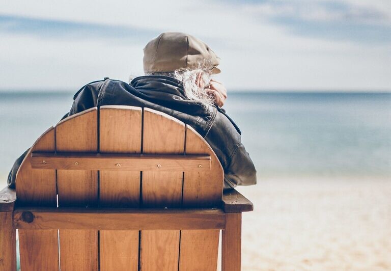 person sitting on brown wooden chair in seashore