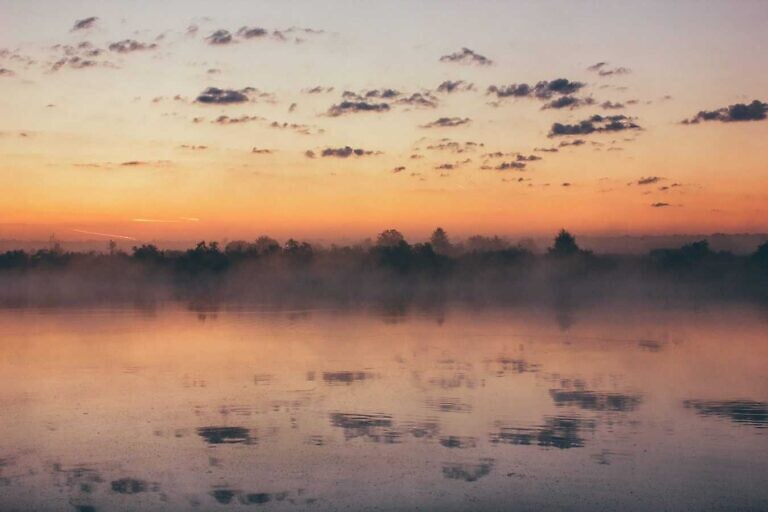 landscape photography of body of water across mountain at sunset