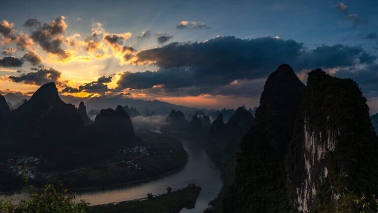 silhouette of mountain under cloudy sky during sunset