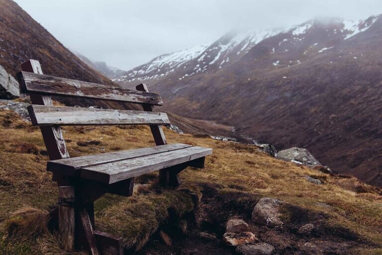 brown wooden bench on mountainside at daytime