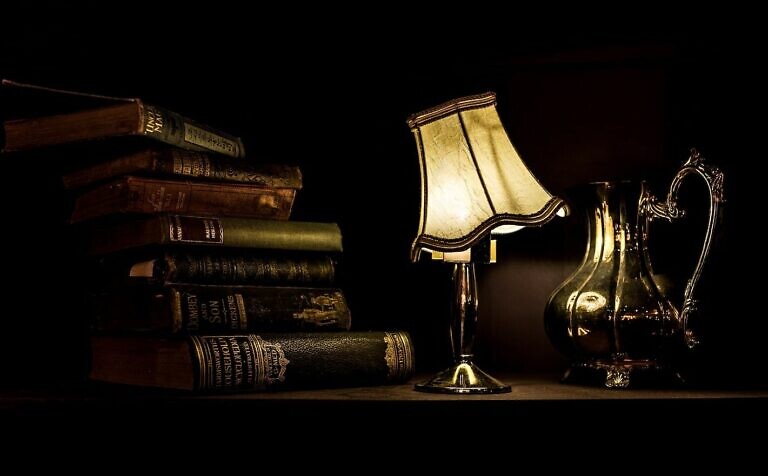 turned on desk lamp beside pile of books